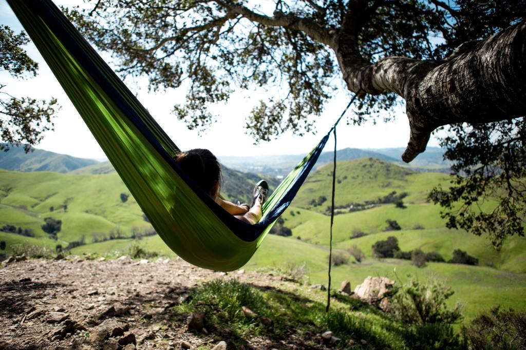 woman laying in hammock on hill side